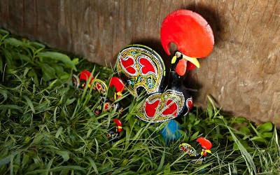 Photo of tin rooster sculptures in grass.