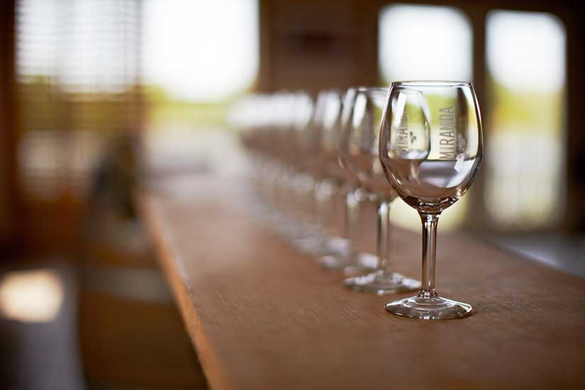 Photo of a row of wine glasses on a bar.